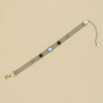 Elegant Clover Charm Bracelet – A gold-tone mesh chain bracelet adorned with black, gold, and pearl-white clover charms, featuring an adjustable closure for a perfect fit