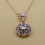 Radiant Halo Pendant Necklace – A gold-tone necklace with a round-cut center stone, surrounded by two halos of sparkling accents for an elegant and sophisticated look.